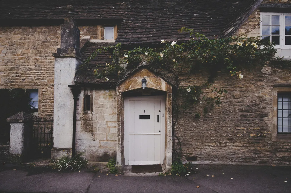 Traditional stone home with timber windows and a painted timber door